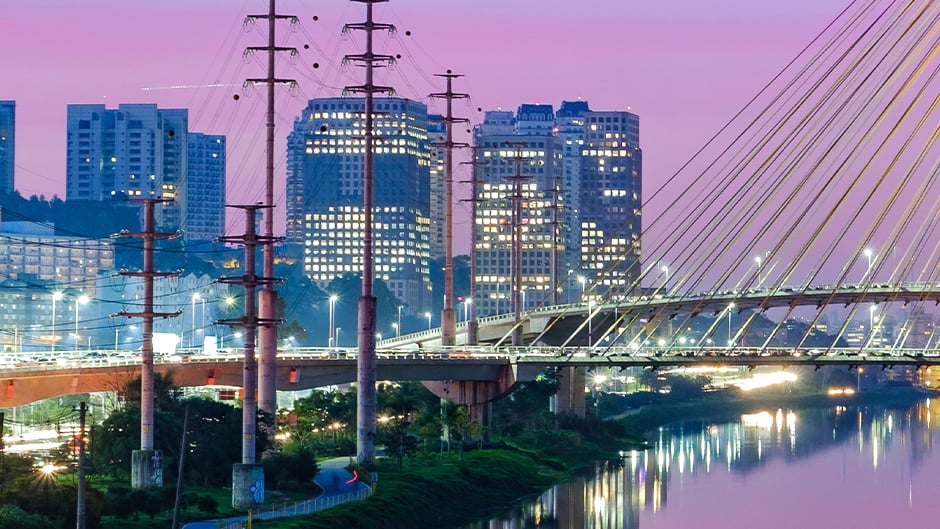 City buildings with purple sky and bridge in foreground