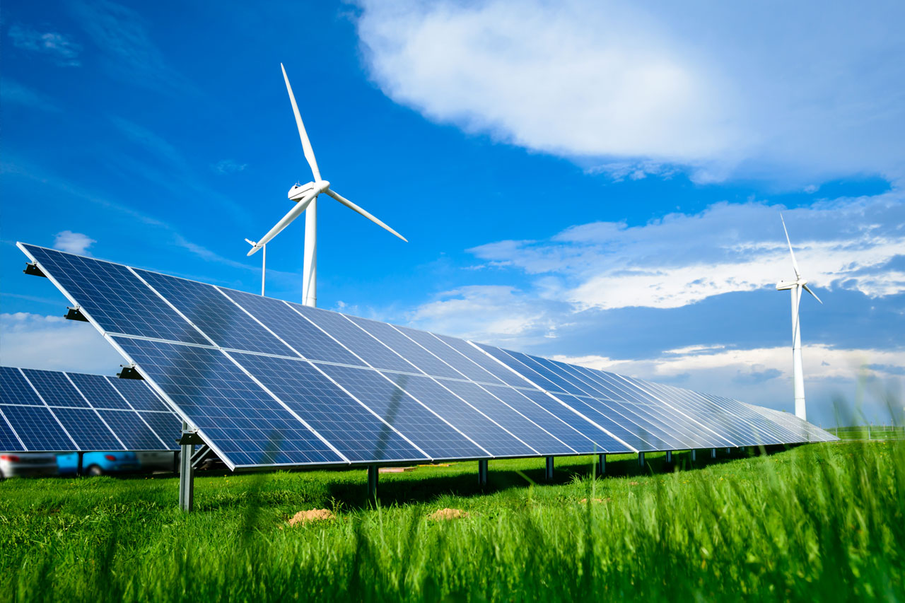 Solar energy panels and windmills against blue sky on summer day