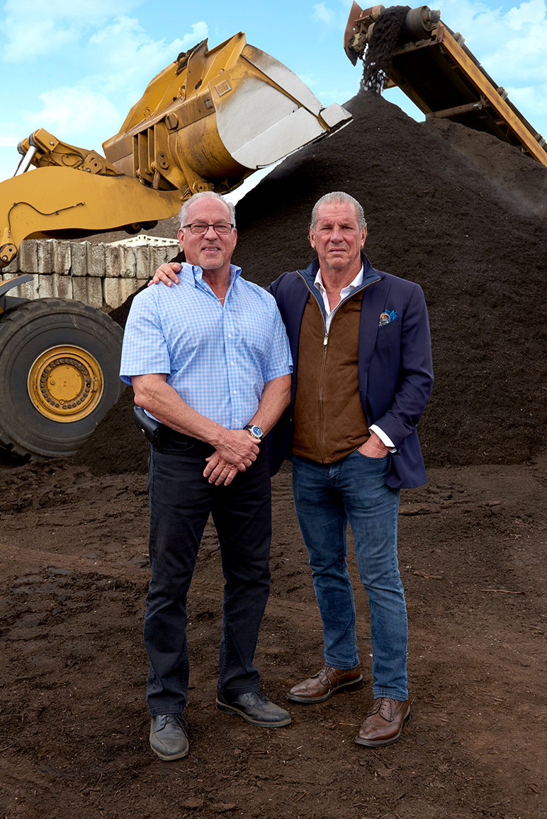 arnold and charles vigliotti in front of dirt hills with construction equipment